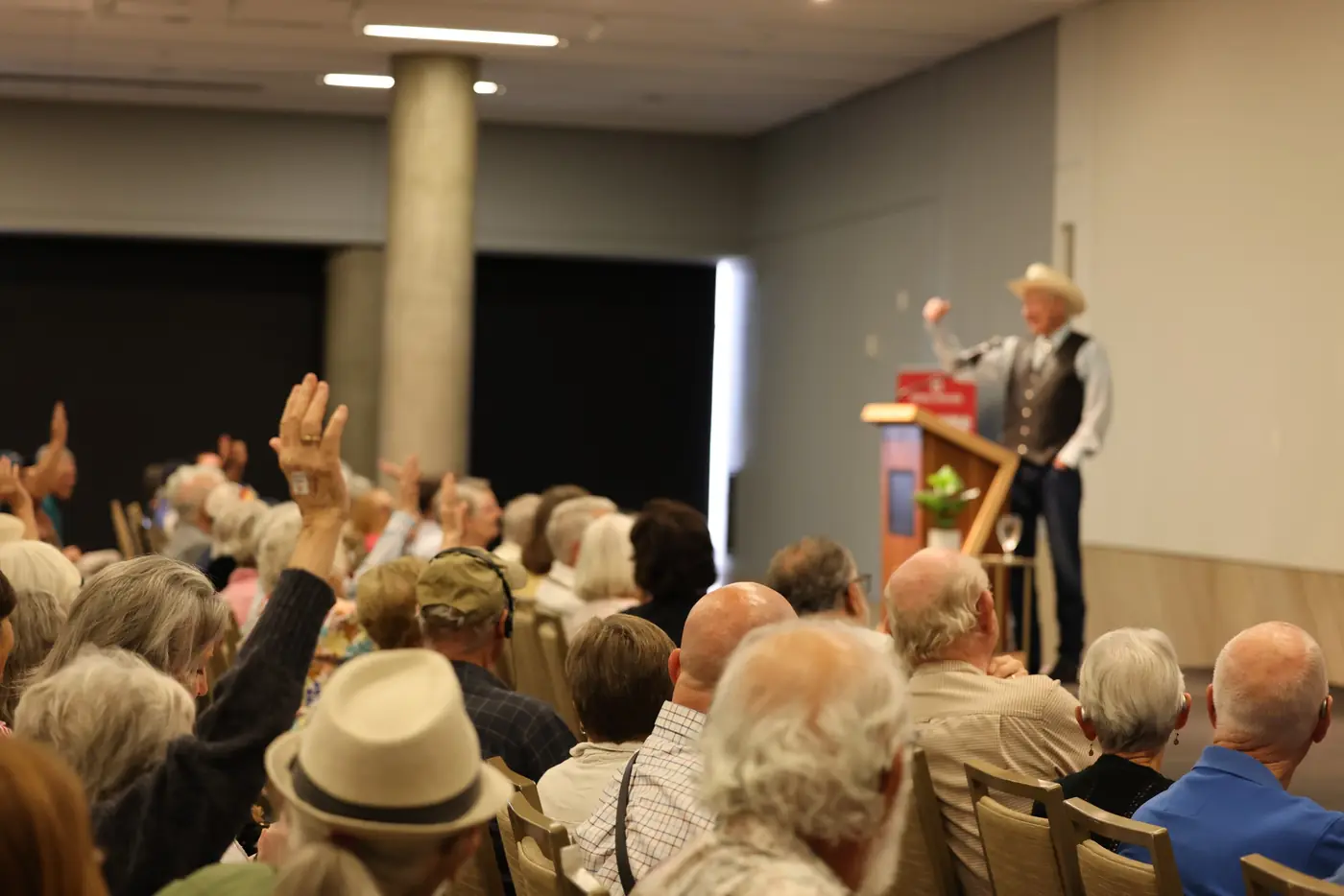 Audience members raising their hands as Ken Salazar speaks